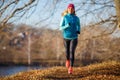 Young woman running in autumn park at sunny day Royalty Free Stock Photo