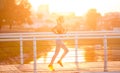 Young woman running on bridge early in morning, sun flare effect Royalty Free Stock Photo