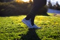 Young woman running on the field in the morning. Active person outdoor. Close-up on shoe