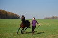 Young woman running with horse on green field on sunny summer day, copy space. Royalty Free Stock Photo