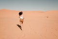 Young woman running through the sand dunes in the desert