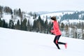 Young woman running on snow in winter mountains wearing warm clothing gloves in snowy weather Royalty Free Stock Photo