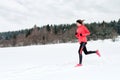 Young woman running on snow in winter mountains wearing warm clothing gloves in snowy weather Royalty Free Stock Photo