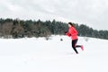 Young woman running on snow in winter mountains wearing warm clothing gloves in snowy weather Royalty Free Stock Photo