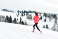 Young woman running on snow in winter mountains wearing warm clothing gloves in snowy weather Royalty Free Stock Photo