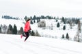 Young woman running on snow in winter mountains wearing warm clothing gloves in snowy weather Royalty Free Stock Photo