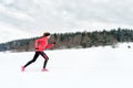 Young woman running on snow in winter mountains wearing warm clothing gloves in snowy weather Royalty Free Stock Photo