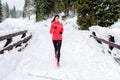 Young woman running on snow in winter mountains wearing warm clothing gloves in snow weather Royalty Free Stock Photo