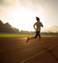 Young woman running during sunny morning on stadium track Royalty Free Stock Photo