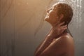 Young woman runs hands on face standing under shower water Royalty Free Stock Photo