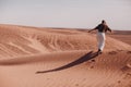 Young woman runs on sand dunes in desert Sahara