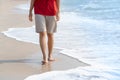 Young woman`s bare feet with a wave coming and enjoying to travel on tropical beach in sunlight Royalty Free Stock Photo