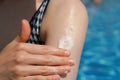A young woman's hand applies sunscreen to the skin of her shoulder against the background of a blue swimming pool close-up. Royalty Free Stock Photo