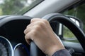 Young woman`s hand is holding the black steering wheel of a car Royalty Free Stock Photo