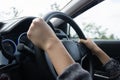 Young woman`s hand is holding the black steering wheel of a car Royalty Free Stock Photo