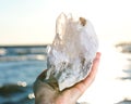 Young woman`s hand holding Himalayan Clear Quartz Laser Cluster