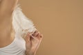 Young Woman`s Hand Touhing Her Armpit With White Feather On Beige Background. Beautiful Body Care Concepts Royalty Free Stock Photo