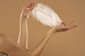 Young Woman`s Hand Touhing Her Skin With White Feather On Beige Background. Beautiful Body Care Concepts Royalty Free Stock Photo