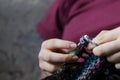 Young woman's hands crocheting colorful wool jacket with yarn sitting in the cozy arm-chair at home. Royalty Free Stock Photo