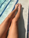 Young womanÃ¢â¬â¢s long tan legs in bright blue pool water