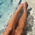 Young womanÃ¢â¬â¢s long tan legs in bright blue pool water