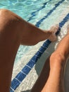 Young womanÃ¢â¬â¢s long tan legs in bright blue pool water Royalty Free Stock Photo