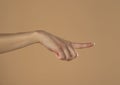 Young woman`s palm touching imaginary product with index finger. Isolated on beige background