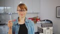 young woman with safety glasses holding a spanner upwards in the kitchen, tools in the background Royalty Free Stock Photo