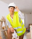 Young woman in safety vest, hardhat and bared legs posing in apartment during renovation Royalty Free Stock Photo