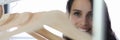 Young woman salesman stands near empty hangers in clothing store closeup