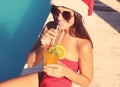 Young woman in Santa Claus hat with refreshing drink near swimming pool. Christmas vacation Royalty Free Stock Photo