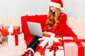 young woman in Santa Claus hat  using laptop  meets Christmas New Year via video call with family  sitting on sofa at home with Royalty Free Stock Photo