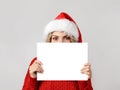 Young woman in santa hat covering her face with blank white paper Royalty Free Stock Photo