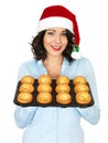 Young Woman in Santa Hat Holding a Tray of Yorkshire Puddings Royalty Free Stock Photo