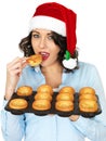 Young Woman in Santa Hat Holding a Tray of Yorkshire Puddings