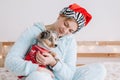 Young woman in Santa hat hugging cute miniature Australian shepherd puppy dog pet. Pet owner celebrating Christmas holiday alone. Royalty Free Stock Photo