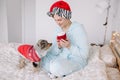 Young woman in Santa hat playing with cute puppy dog pet at home. Pet owner celebrating Christmas holiday alone. Holiday Royalty Free Stock Photo