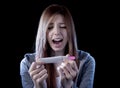 Young woman scared and shocked holding pregnancy test positive result looking unhappy