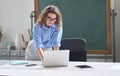 Young woman school teacher, online tutor standing at desk teaching remote class. Royalty Free Stock Photo