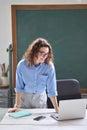 Young woman school teacher, online tutor standing at desk teaching remote class. Royalty Free Stock Photo