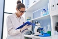 Young woman scientist measuring liquid writing on clipboard at laboratory Royalty Free Stock Photo