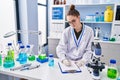 Young woman scientist measuring liquid writing on document at laboratory Royalty Free Stock Photo