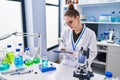 Young woman scientist measuring liquid writing on document at laboratory Royalty Free Stock Photo