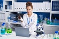 Young woman scientist using laptop holding bottle at laboratory Royalty Free Stock Photo