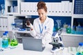 Young woman scientist using laptop holding bottle at laboratory Royalty Free Stock Photo