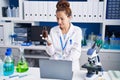 Young woman scientist using laptop holding bottle at laboratory Royalty Free Stock Photo