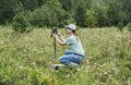 Young woman scientist zoologist sets camera trap for observing wild animals in forest to collect scientific data Environmental