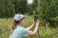 Young woman scientist zoologist sets camera trap for observing wild animals in forest to collect scientific data Environmental