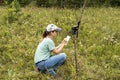 Young woman scientist zoologist writing down data from trap camera to notepad, observing wild animals in reserve taiga forest, Royalty Free Stock Photo