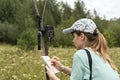 Young woman scientist zoologist writing down data from trap camera to notepad, observing wild animals in reserve taiga forest, Royalty Free Stock Photo